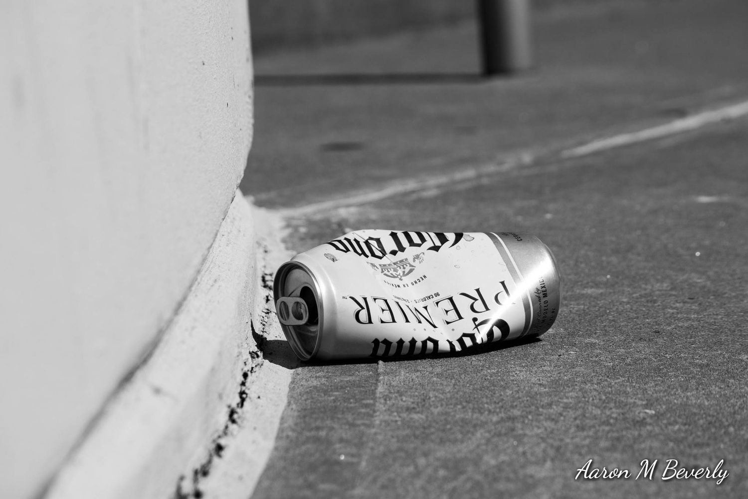 Black and white close-up of spray paint can lying on concrete surface.