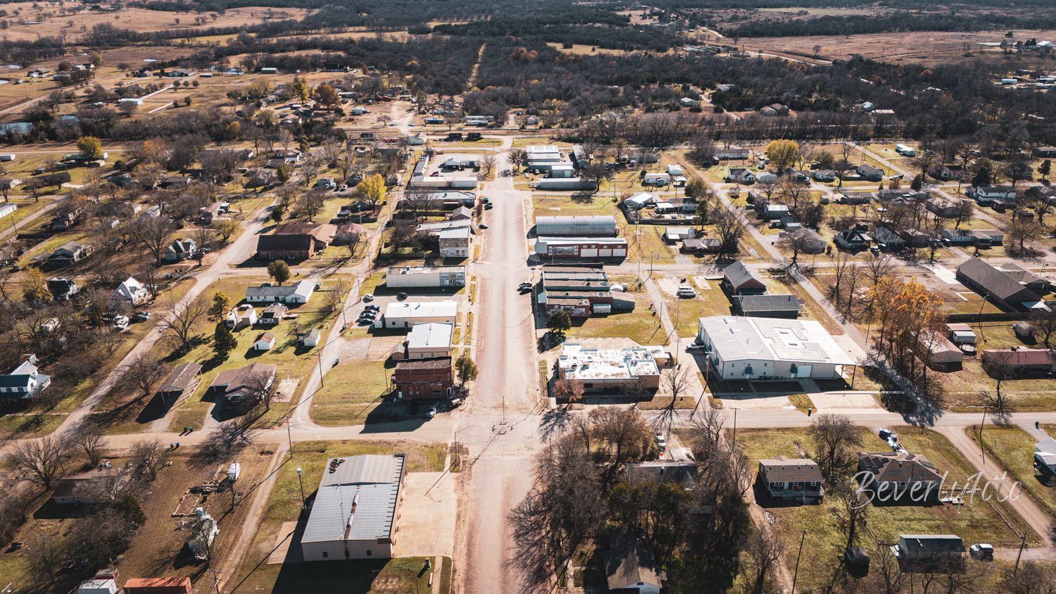 Aerial view of a small rural town with main street running through center and buildings scattered along both sides.