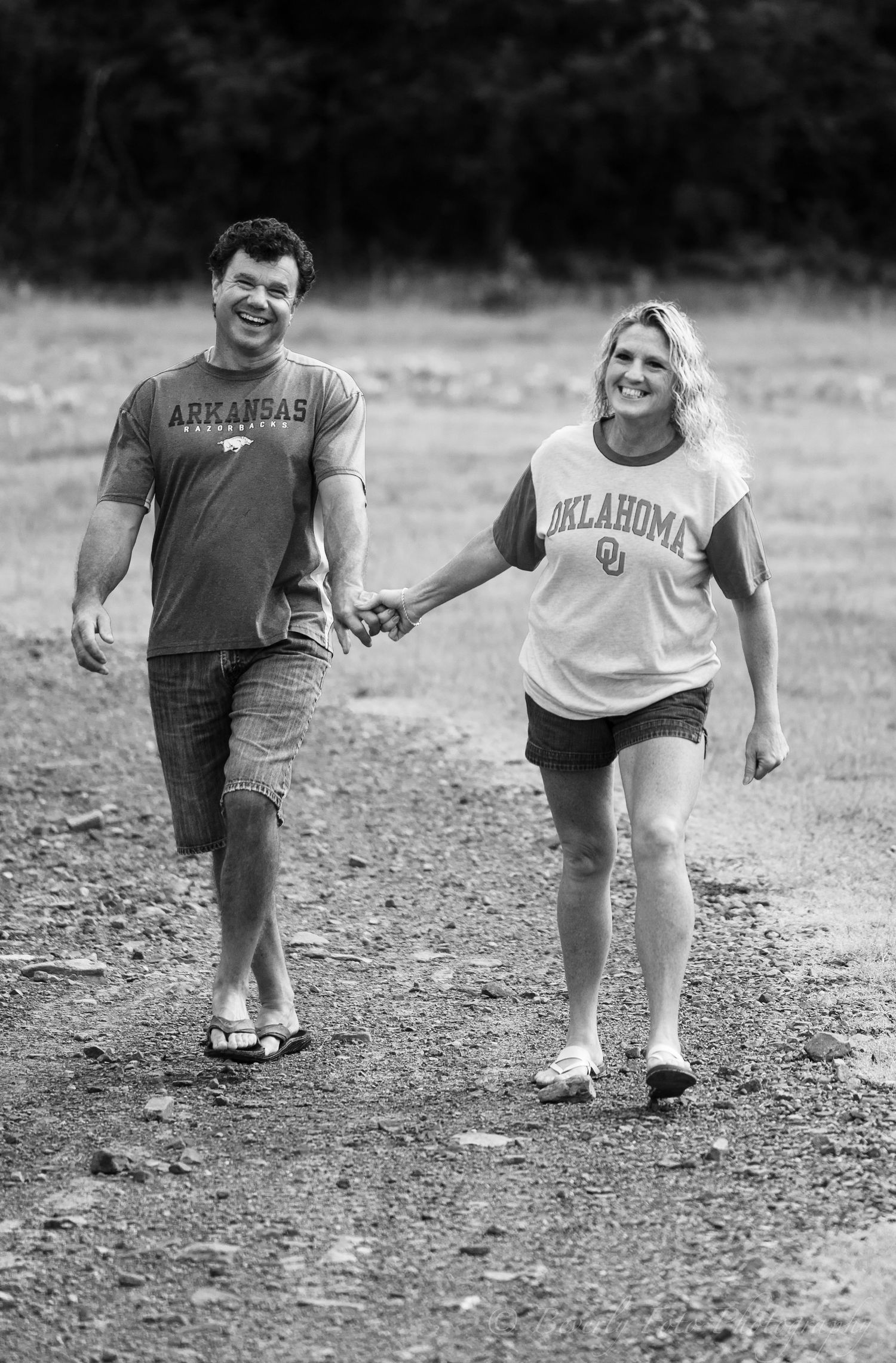 Black and white photo of couple walking together on dirt path.
