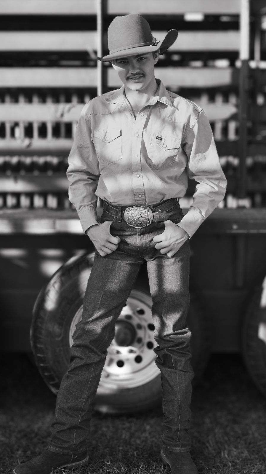 Black and white photo of person wearing western attire and cowboy hat.