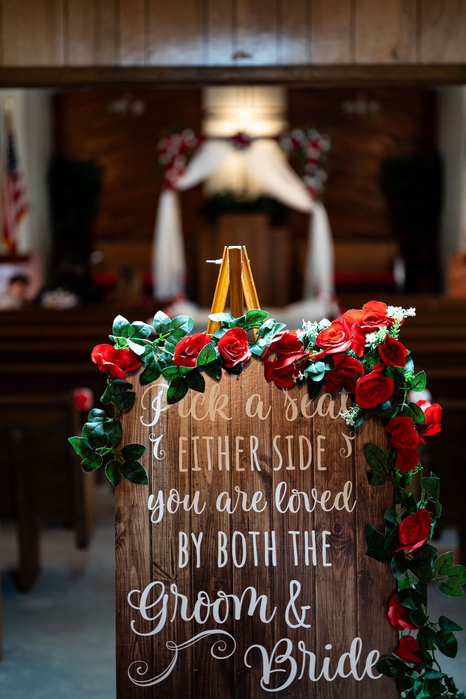 Rustic wooden wedding signs decorated with red and white flowers display welcome messages for guests.