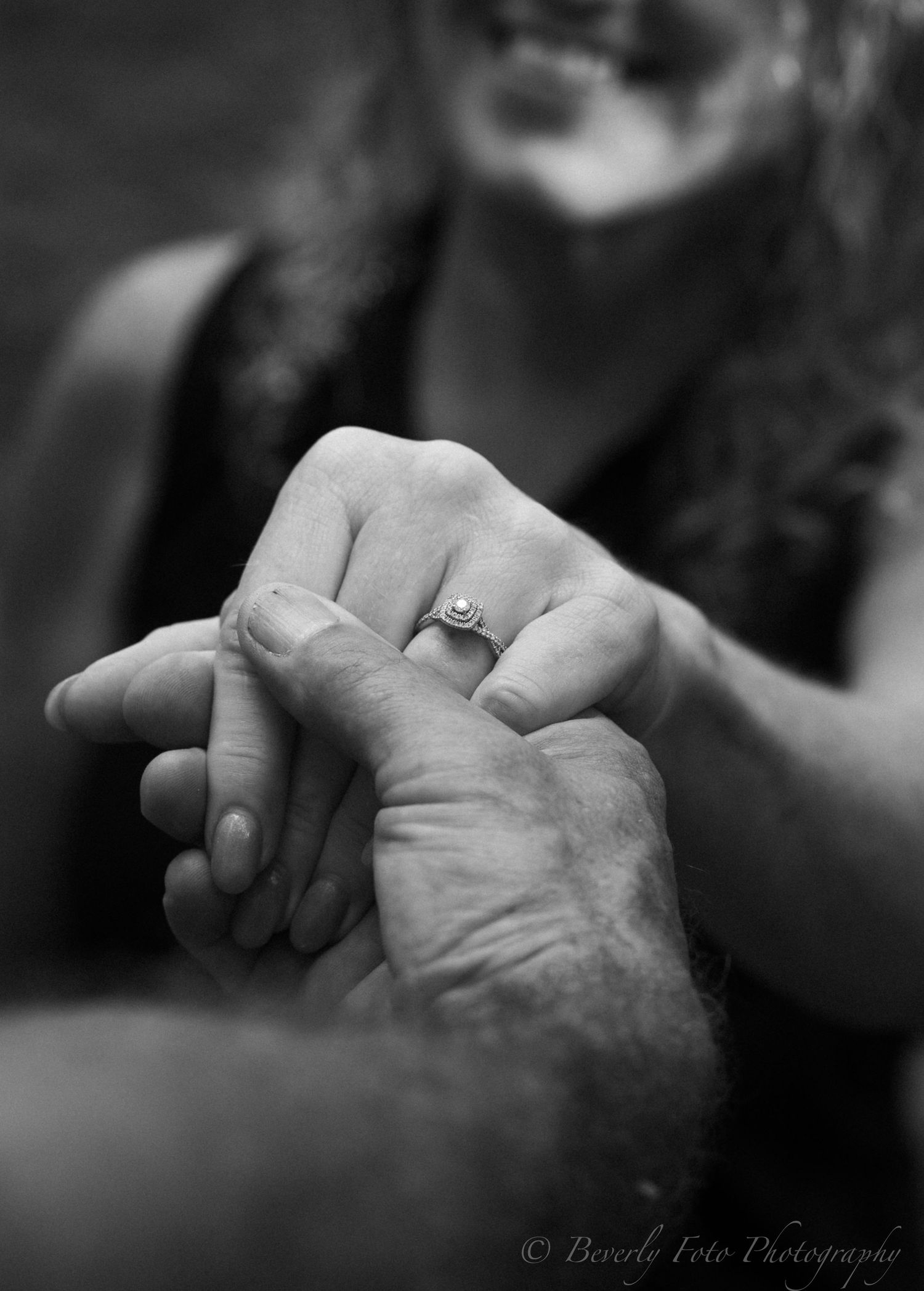 Close-up series of hands with engagement rings in black and white photography.