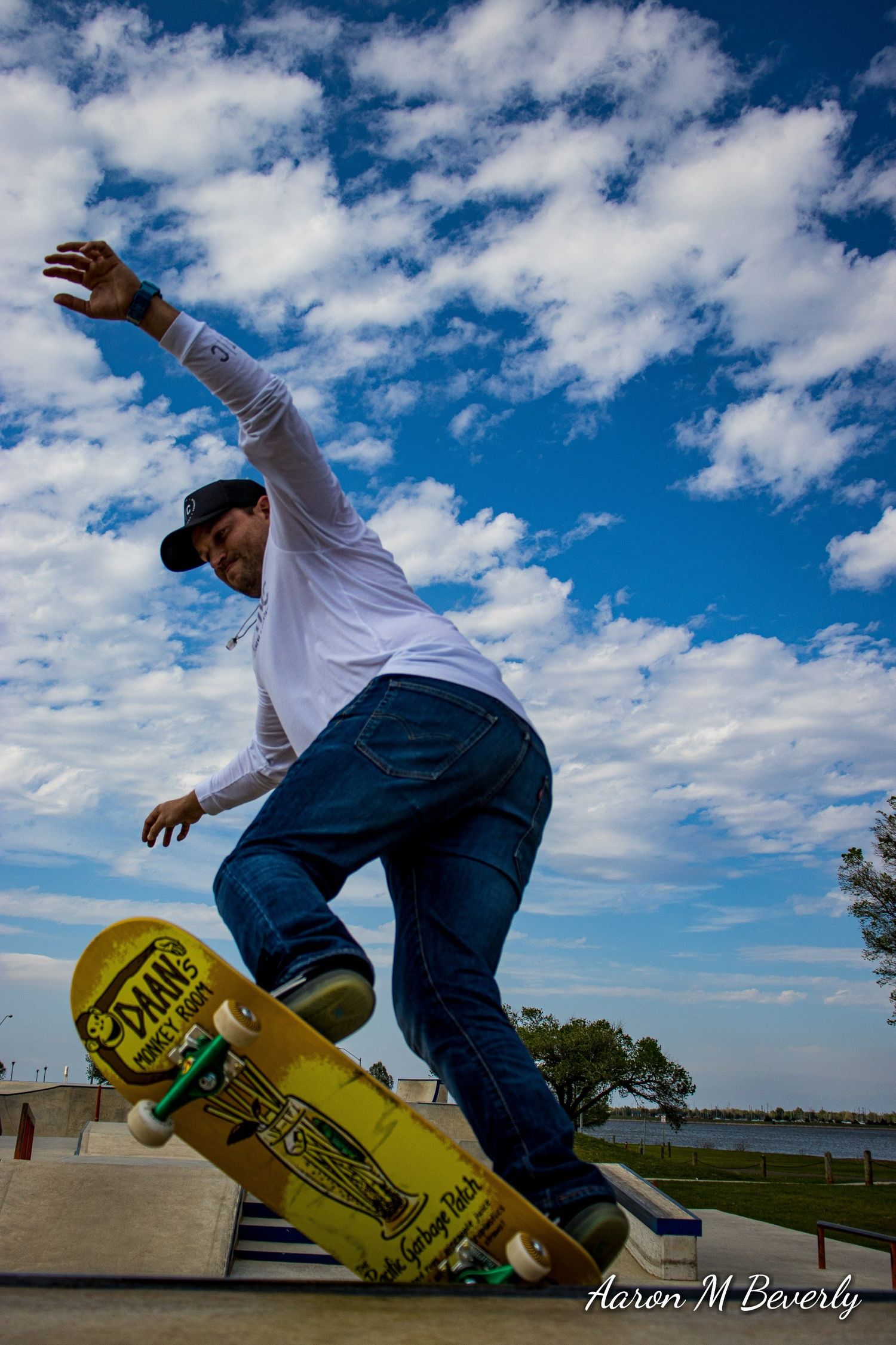 Action sequence of a skateboarder performing tricks against a bright blue sky with white clouds.