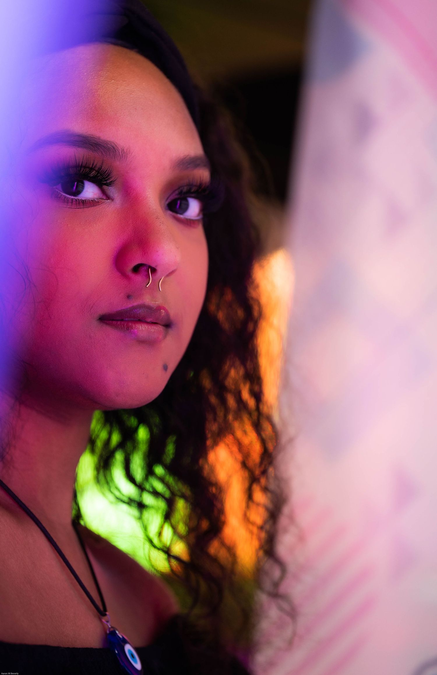 Artistic portrait with vibrant purple and pink lighting effects creating a dramatic atmosphere.