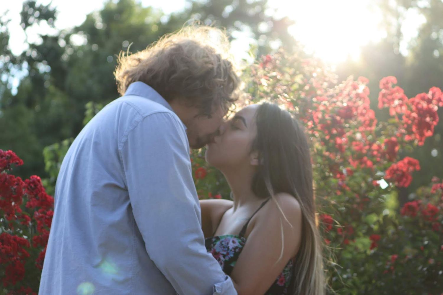 Couple sharing an intimate moment among blooming flowers at sunset.
