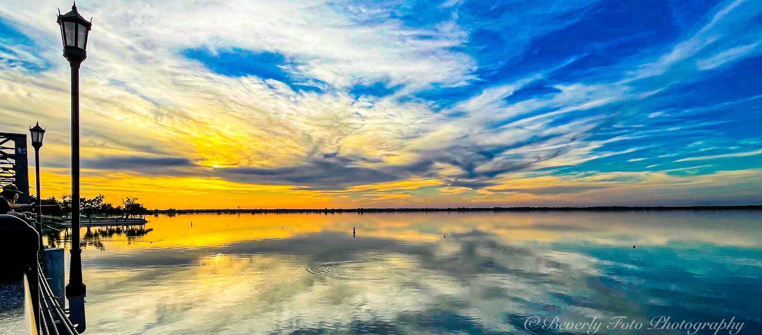 Panoramic sunset skyline with street lamp silhouette against dramatic blue and orange clouds.