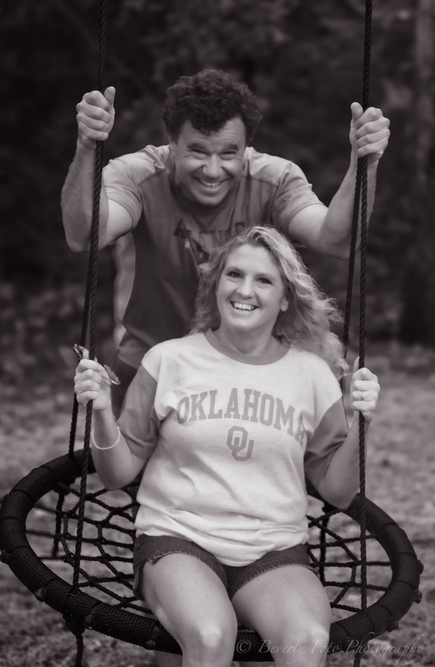 A sequence of black and white photos showing a playful couple enjoying time together on a swing outdoors.