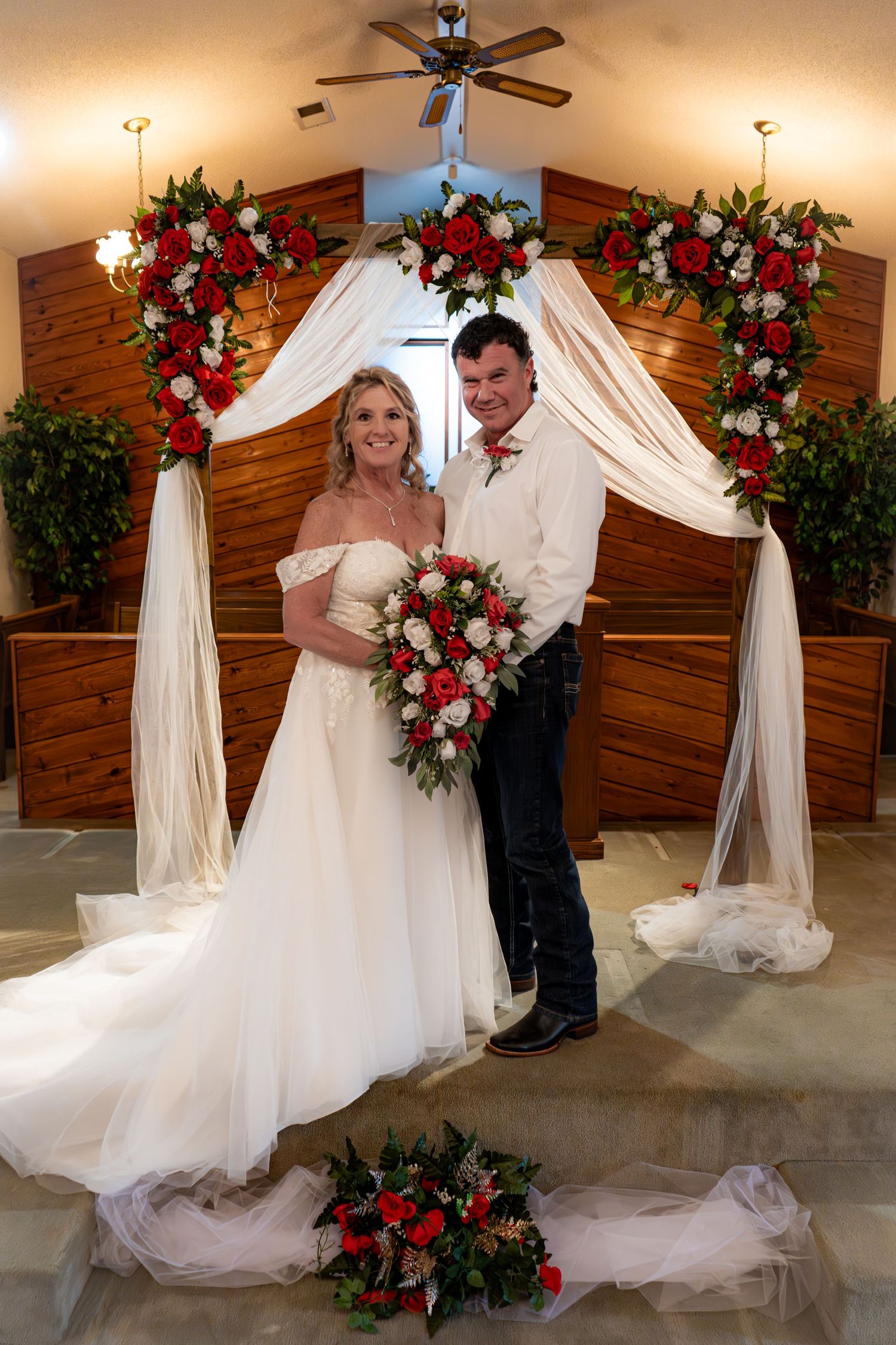 A romantic wedding photo series showing a couple in traditional white dress and suit posing against wooden walls with red floral decor.
