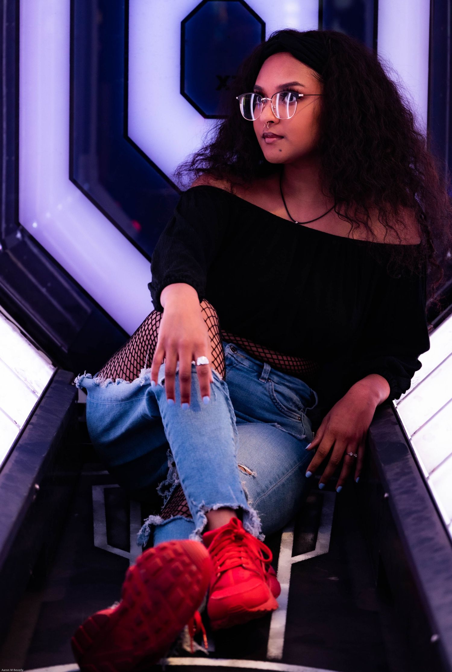 Artistic portrait with purple geometric background and ripped jeans.