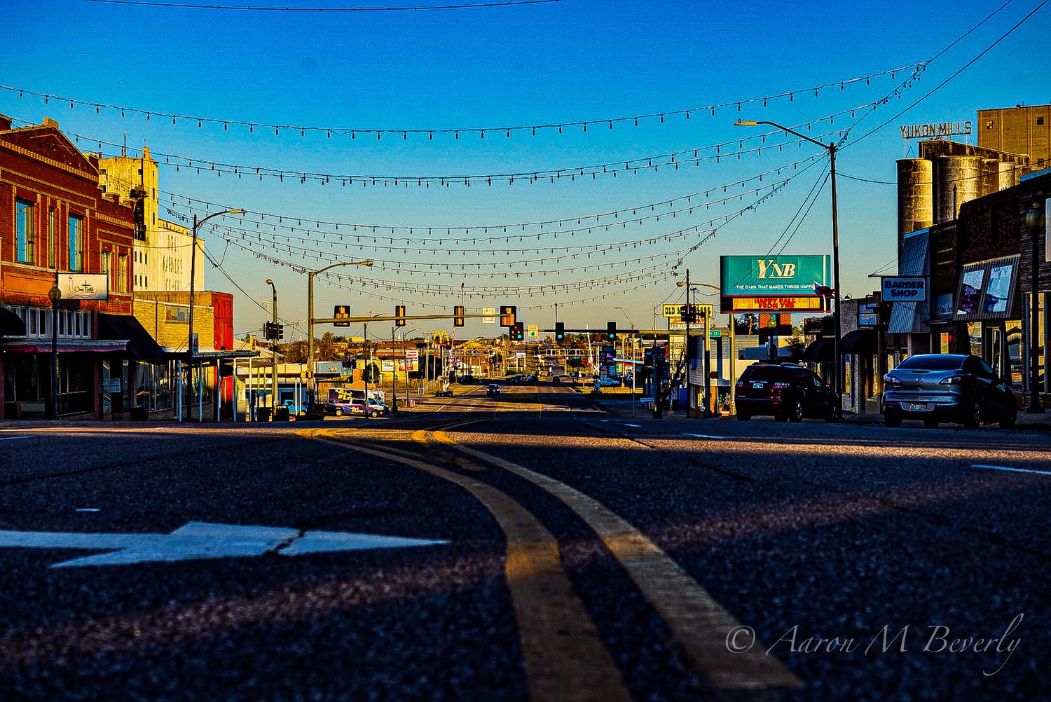 String lights span across a small town main street at dusk.