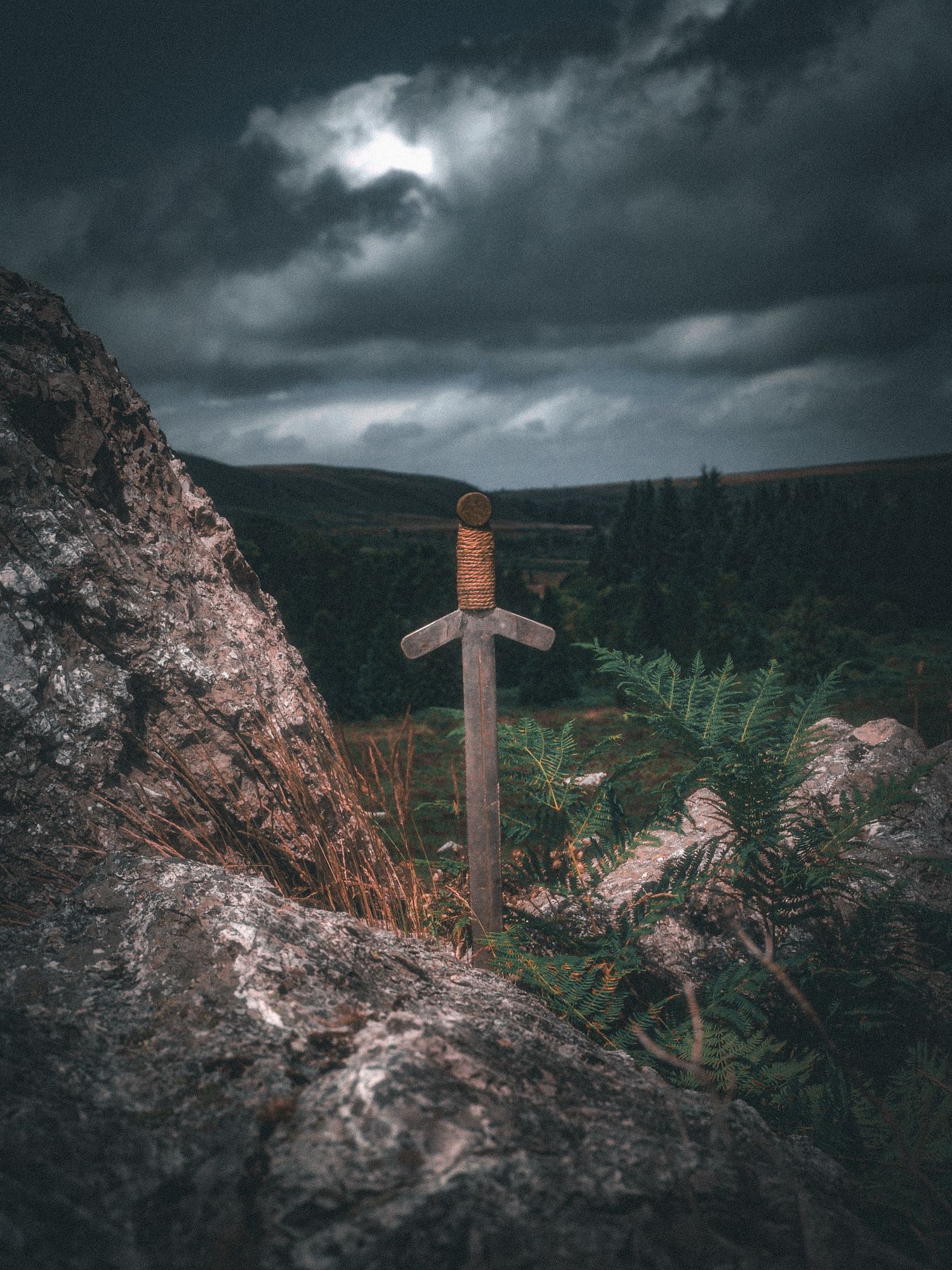 Photo d'une épée plantée dans un rocher et surplombant une vallée. Inspirée de la légende du roi Arthur et de la légende d'Excalibur.