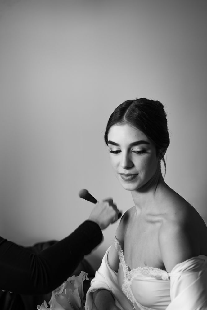 black and white photo of bride getting her makeup done