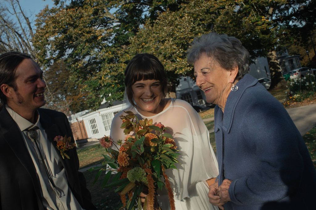 A group of people gather outdoors during a wedding ceremony on a sunny autumn day.