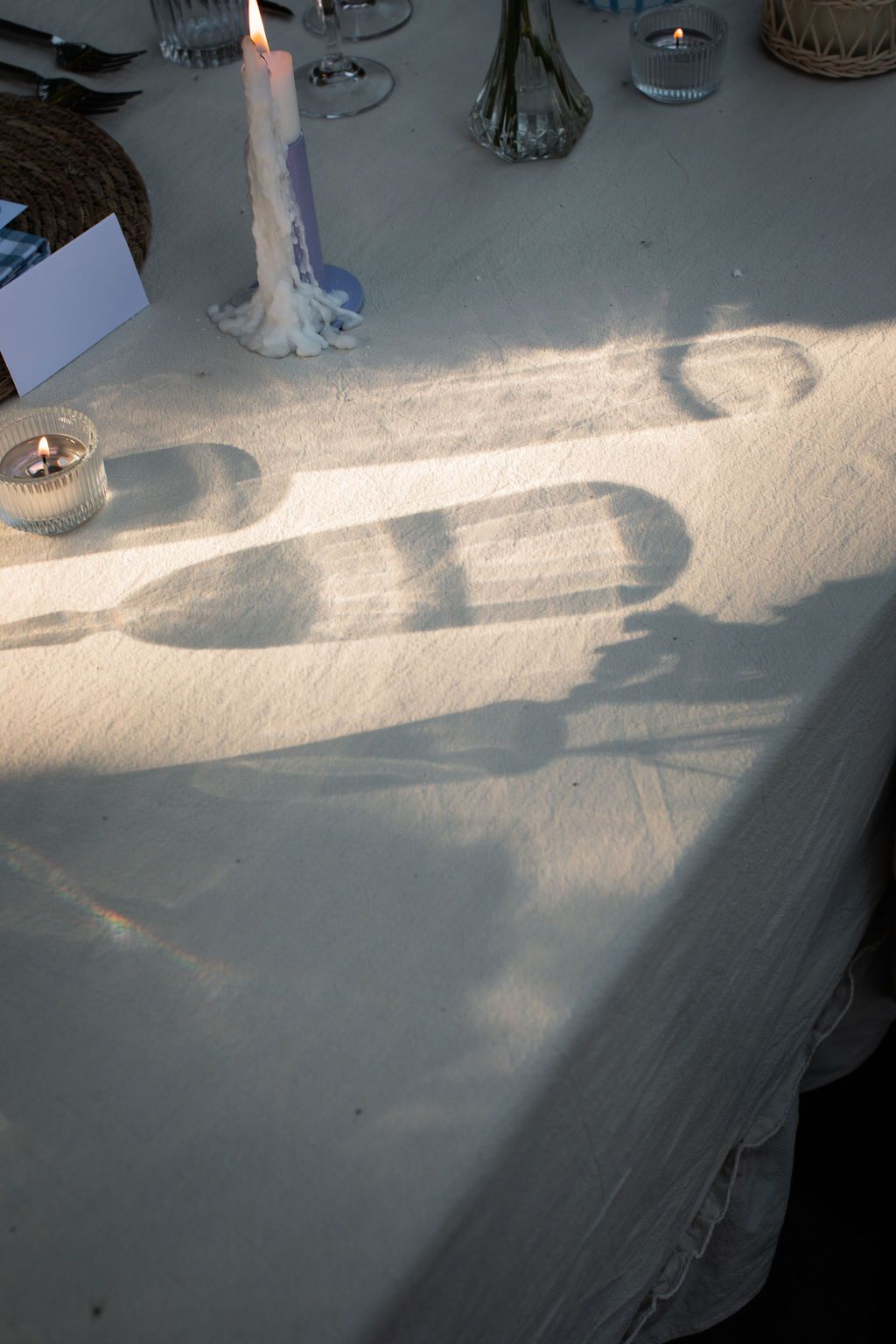 reflection of glasses on white linen at sunset