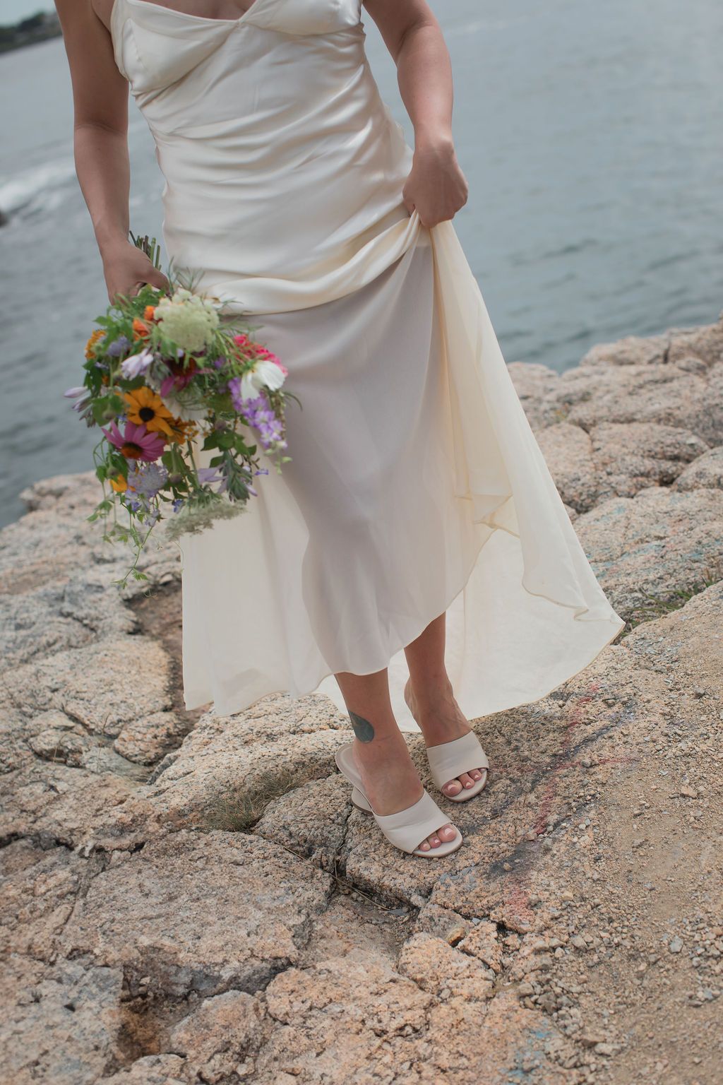 bride showing off her shoes near the ocean