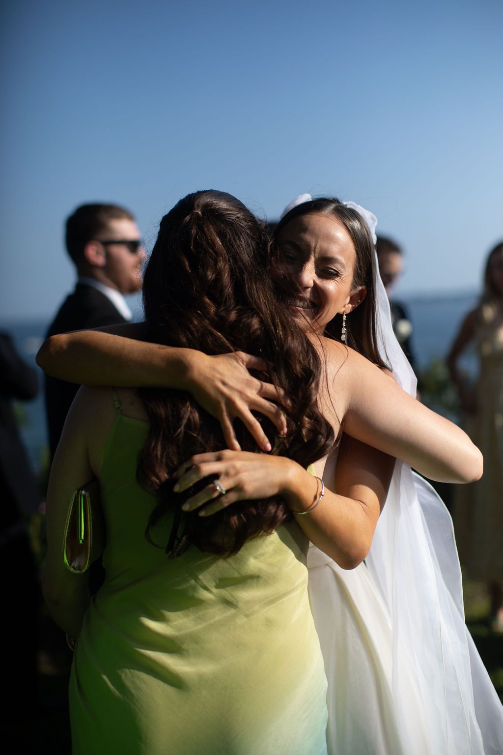 bride hugs and smiles guest with green dress