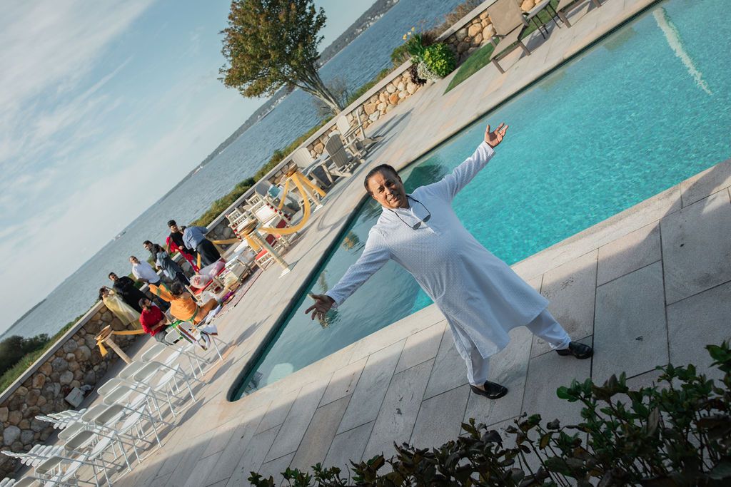 man opening his arms joyfully in front of a pool