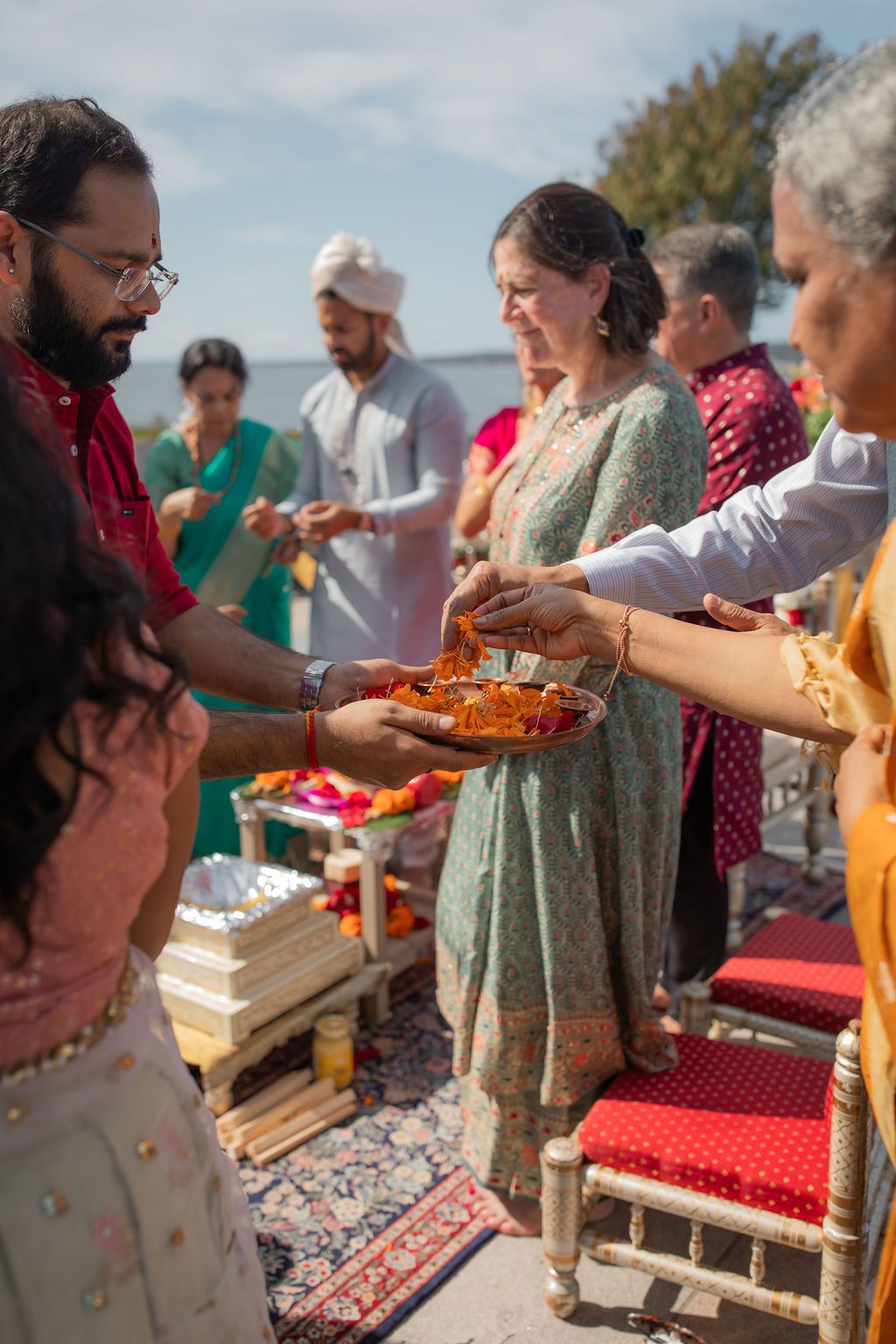 guests collect flower petals from a gold dish at wedding