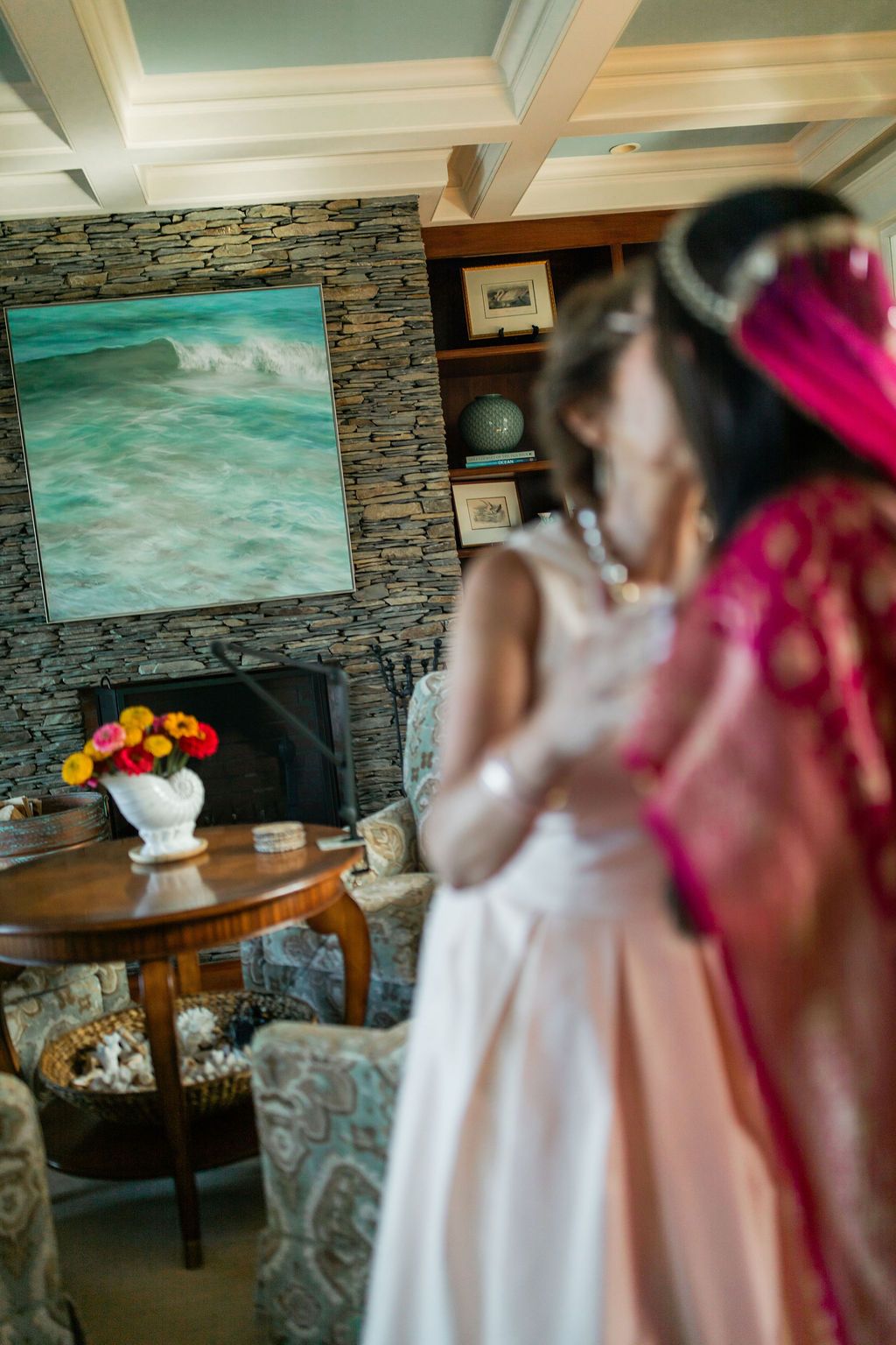 indian bride receiving a kiss from a family member in front of a stone fireplace