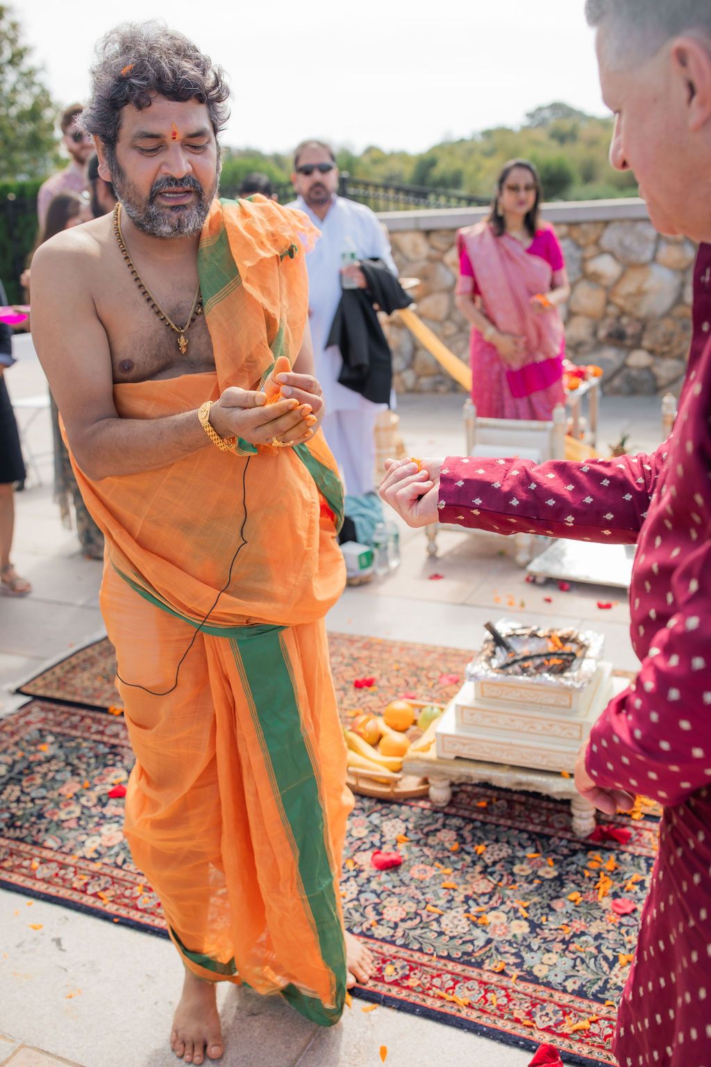 man in orange sari prays at indian wedding ceremony