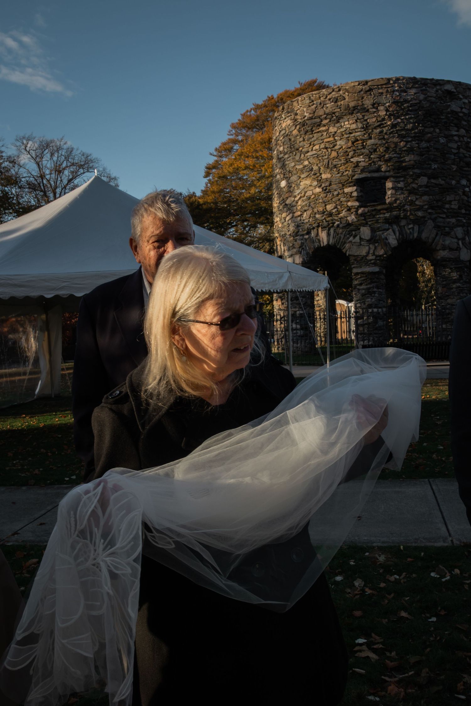 Mother of the bride carries veil in the park at sunset