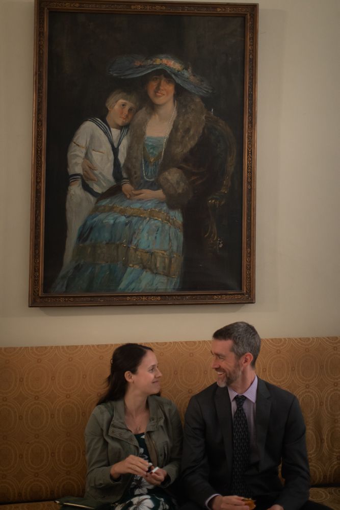 guests sitting on vintage couch talking under fine art painting