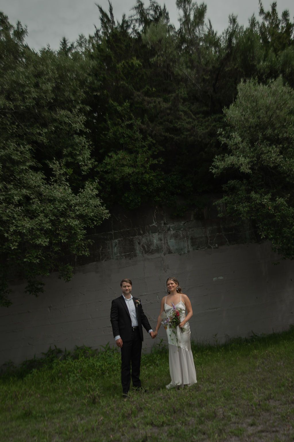 bride and groom in a misty forest clearing surrounded by lush green trees and atmospheric fog