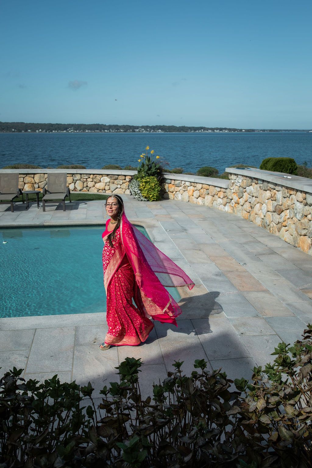 woman in indian wedding dress walks in front of a pool