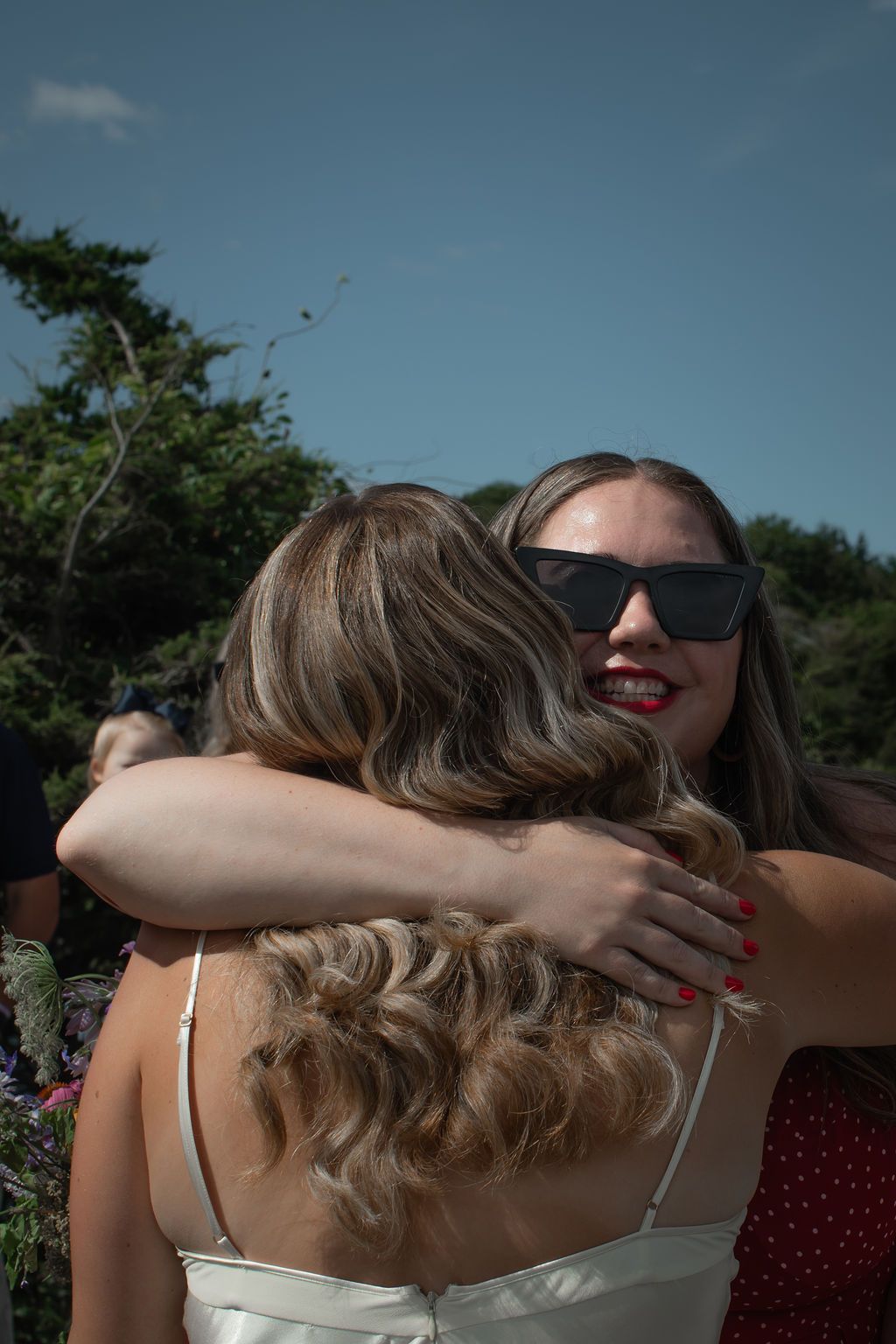 guest with sunglasses hugs bride