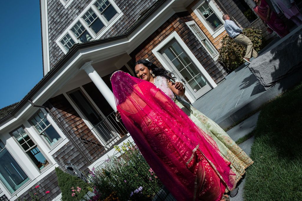 women greet each other outside on a sunny day in front of a house