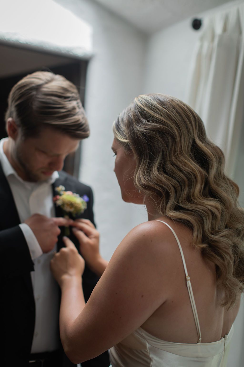 bride pinning flowers on groom