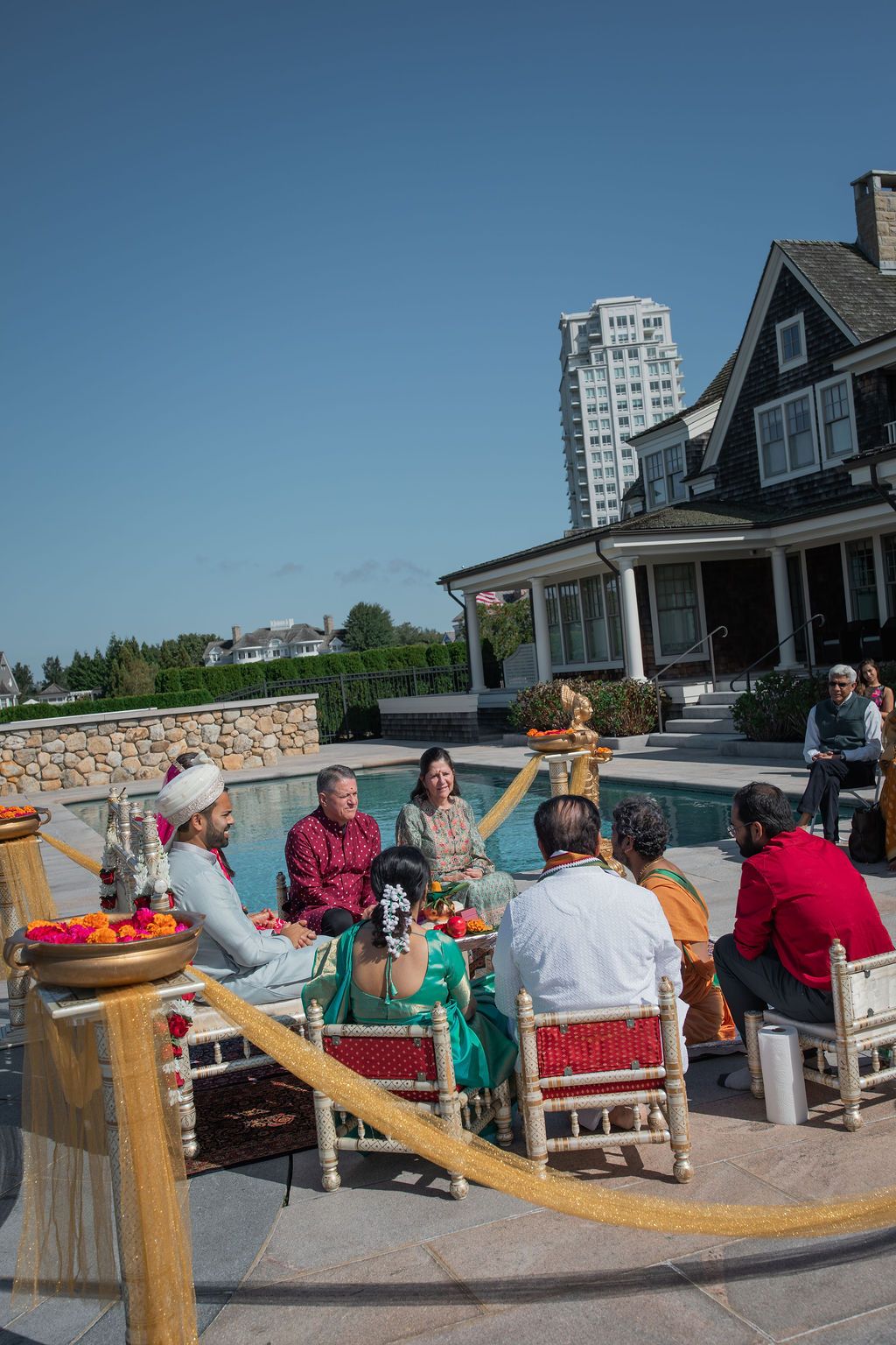 yellow ribbon adorns space outside a backyard pool where family participates in traditional indian wedding ceremony
