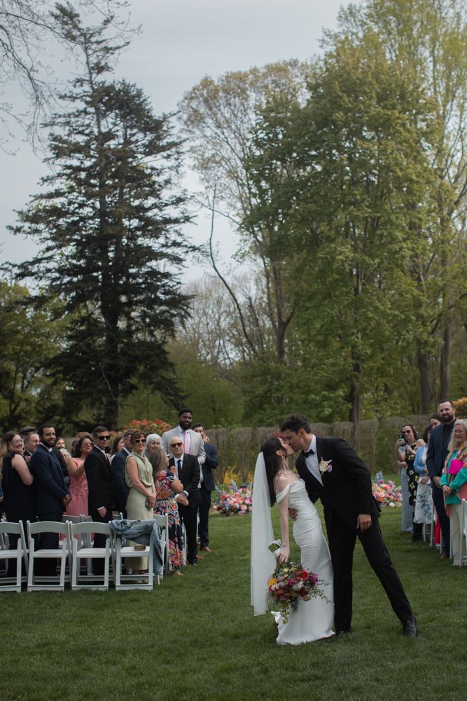 bride and groom kiss in front of guests at outdoor ceremony