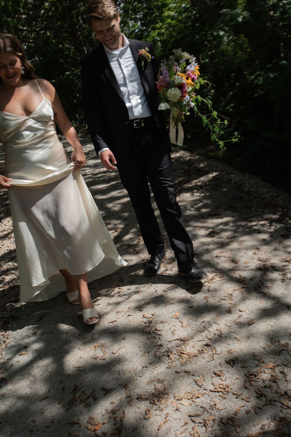 bride and groom walking side by side in shadow of trees