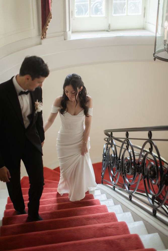 groom leading bride up the red carpeted stairwell