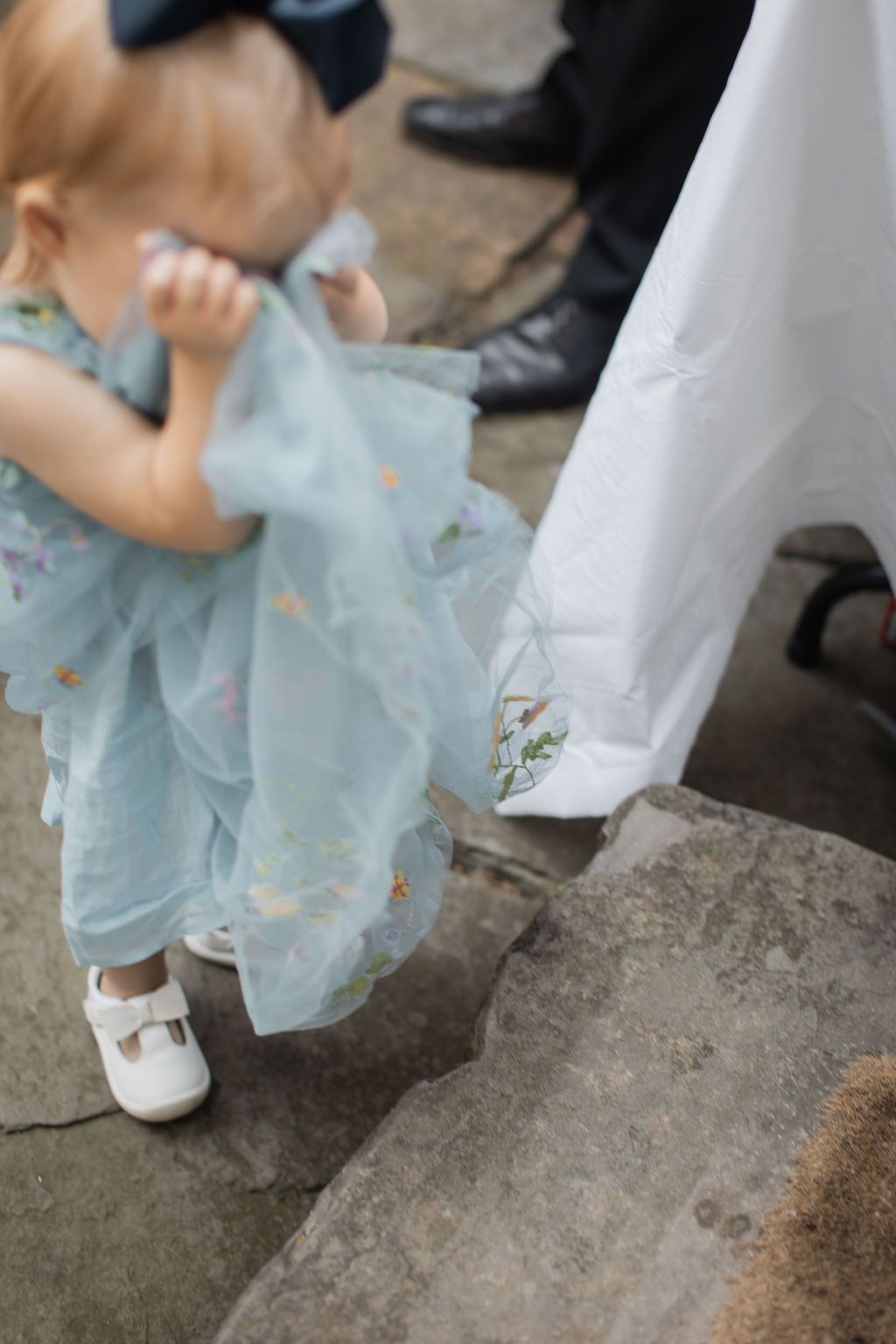 young girl covering her face with a blue dress