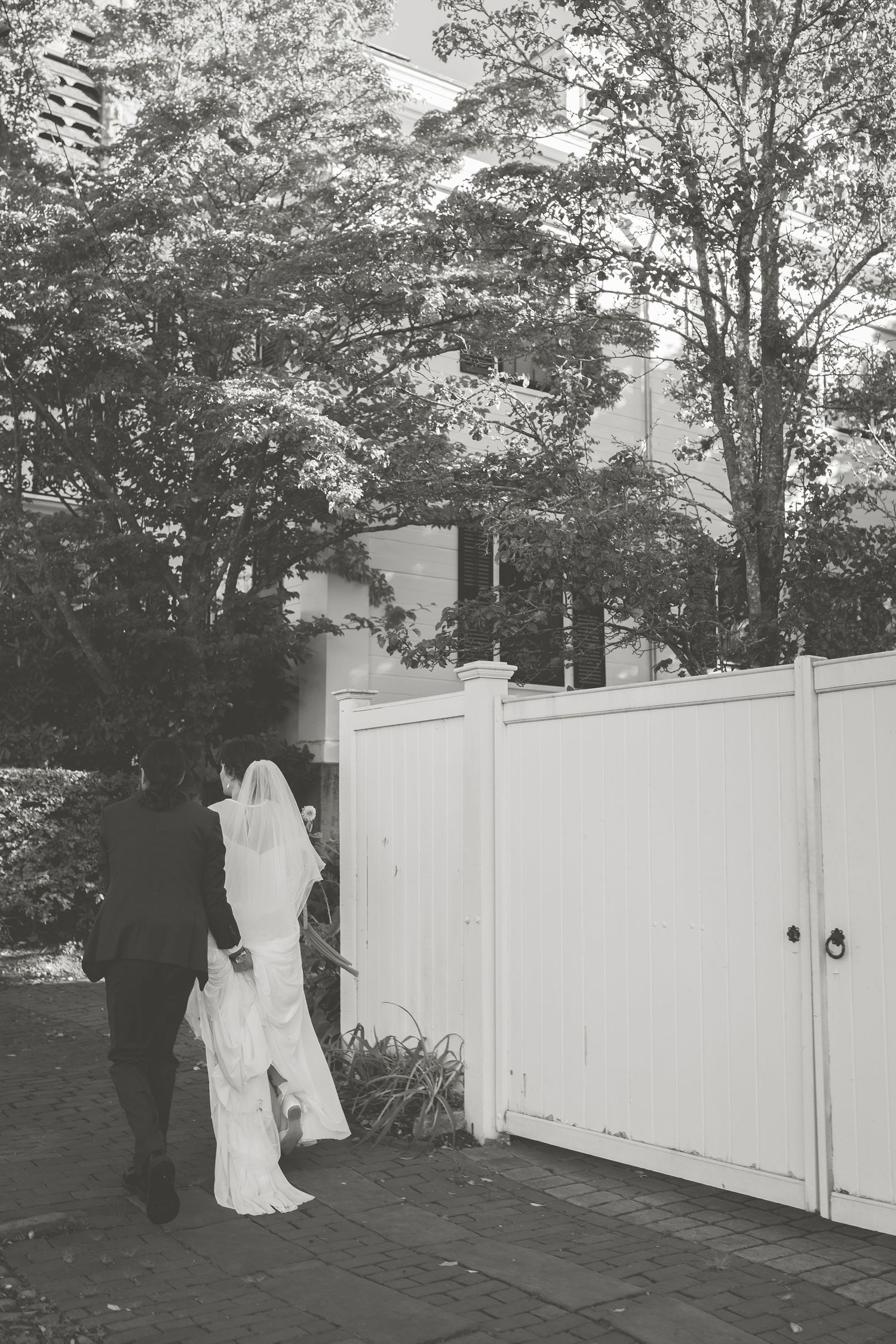 black and white photo of bride and groom near a white fence