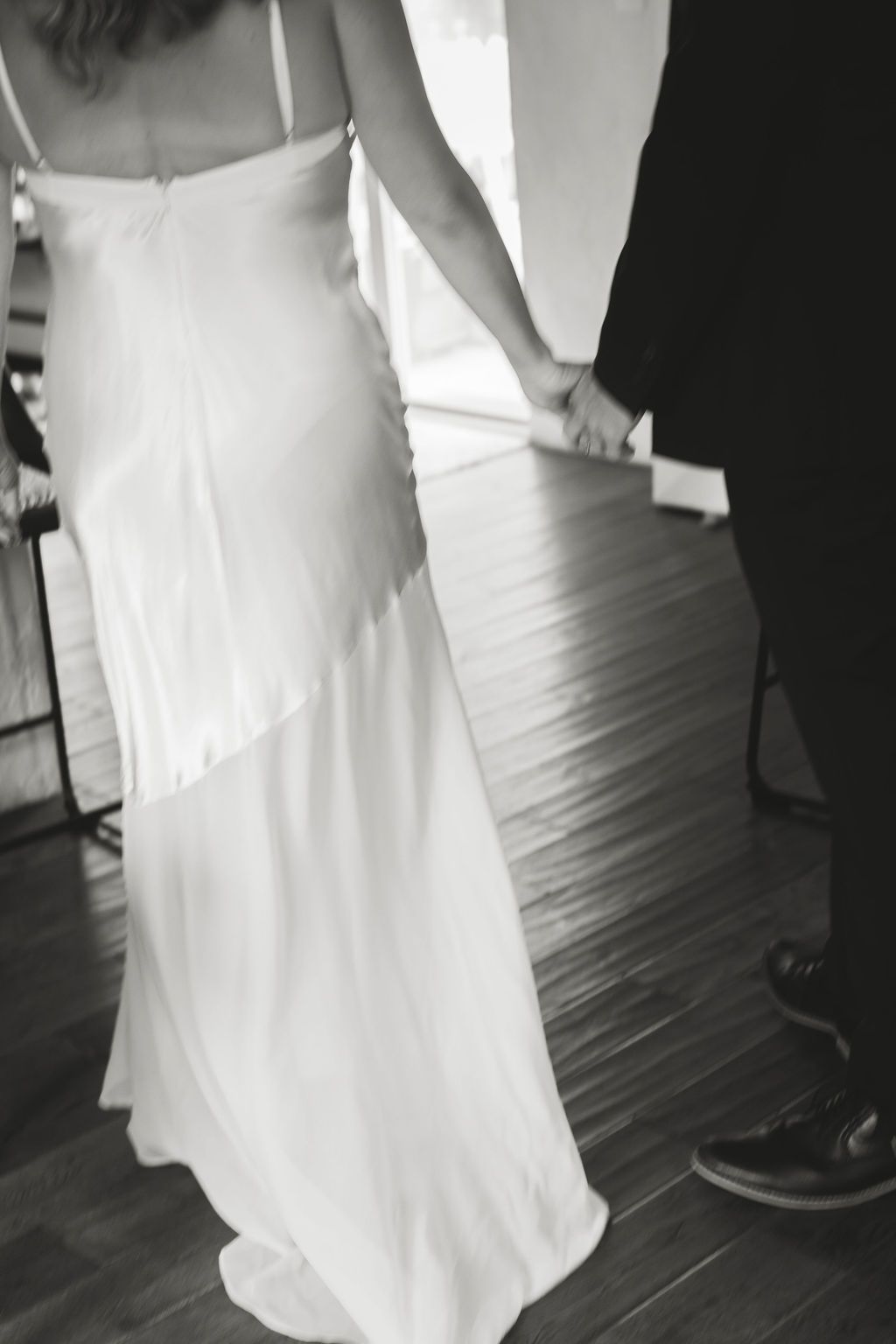 back details of a women in white wedding dress holding hands with groom
