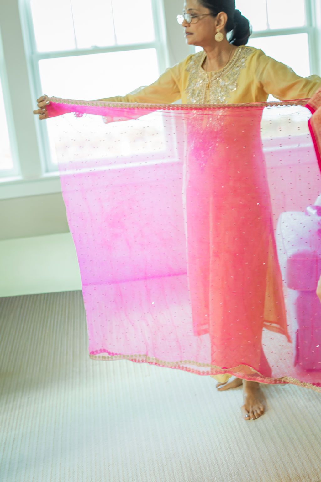 woman holding open a sheer pink scarf