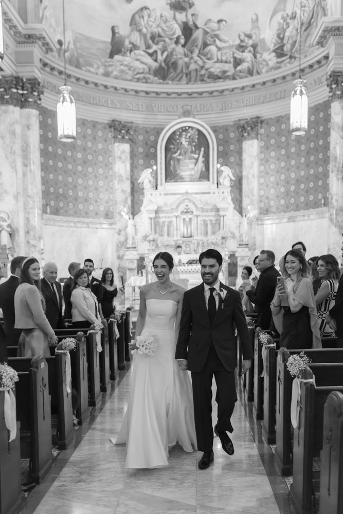 black and white photo of bride and groom walking down the isle