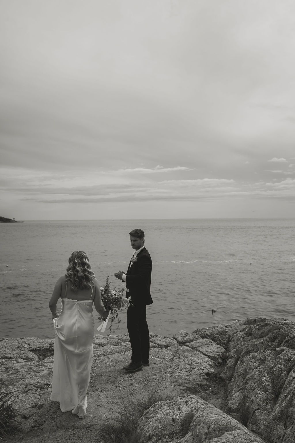black and white photo of bride and groom on ocean cliffs