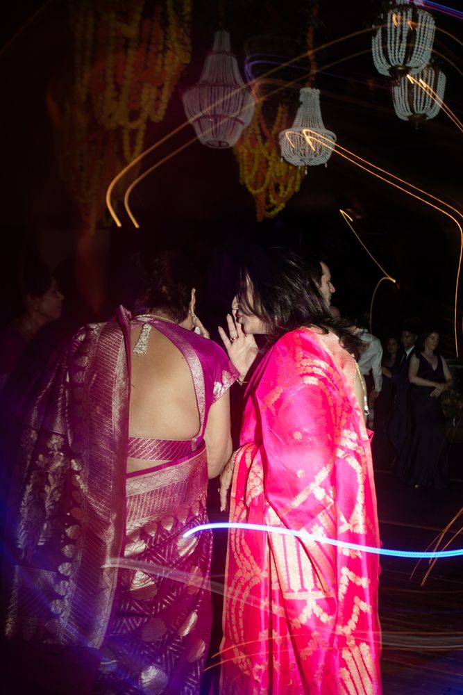 two women in saris talk together on the wedding dance floor