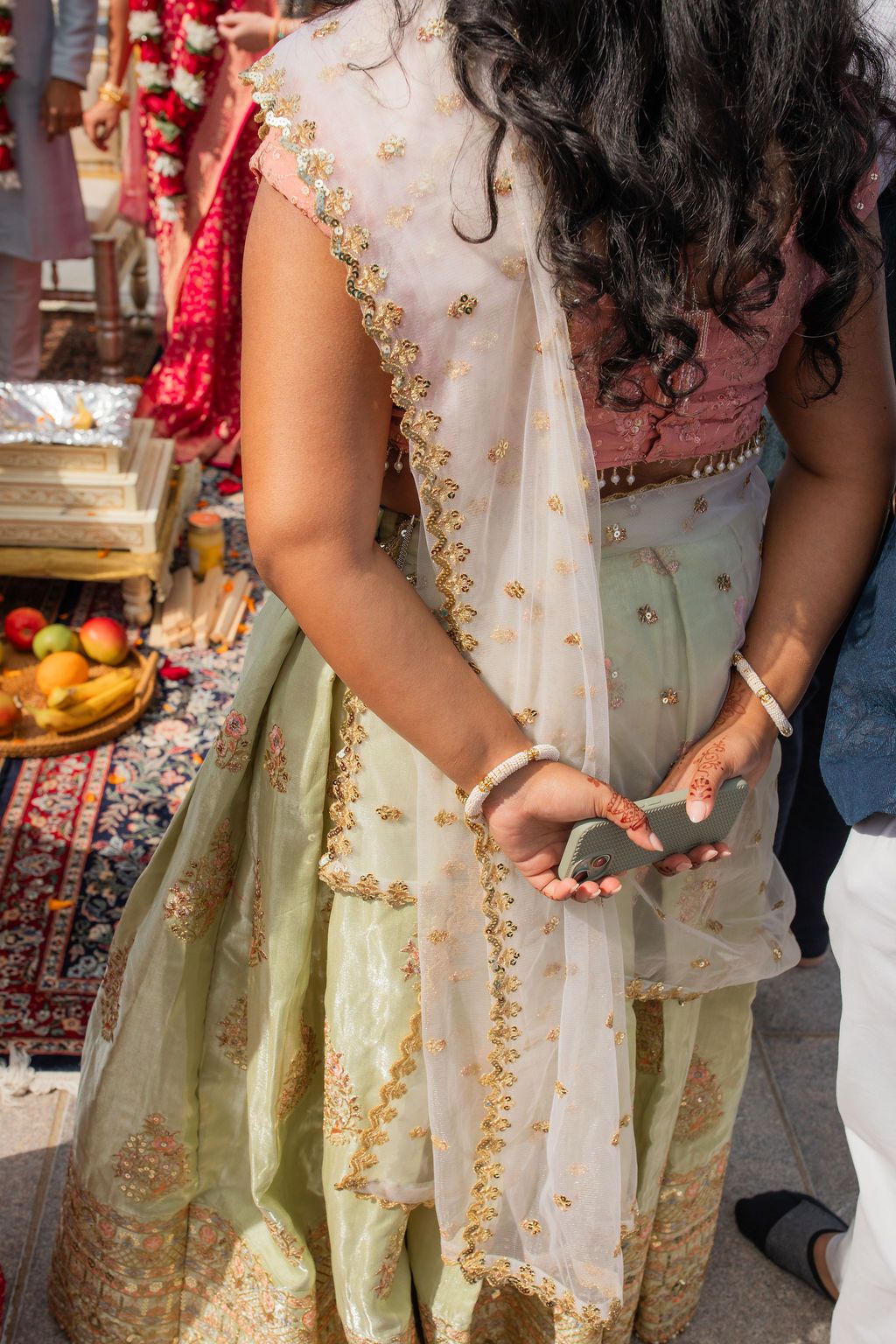woman in indian ceremonial wear holds her hands behind her back