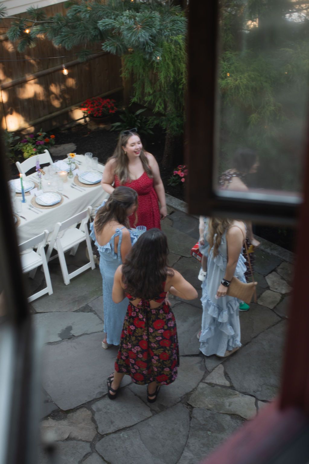 People gathered around outdoor tables at dusk with string lights creating an intimate dining atmosphere.
