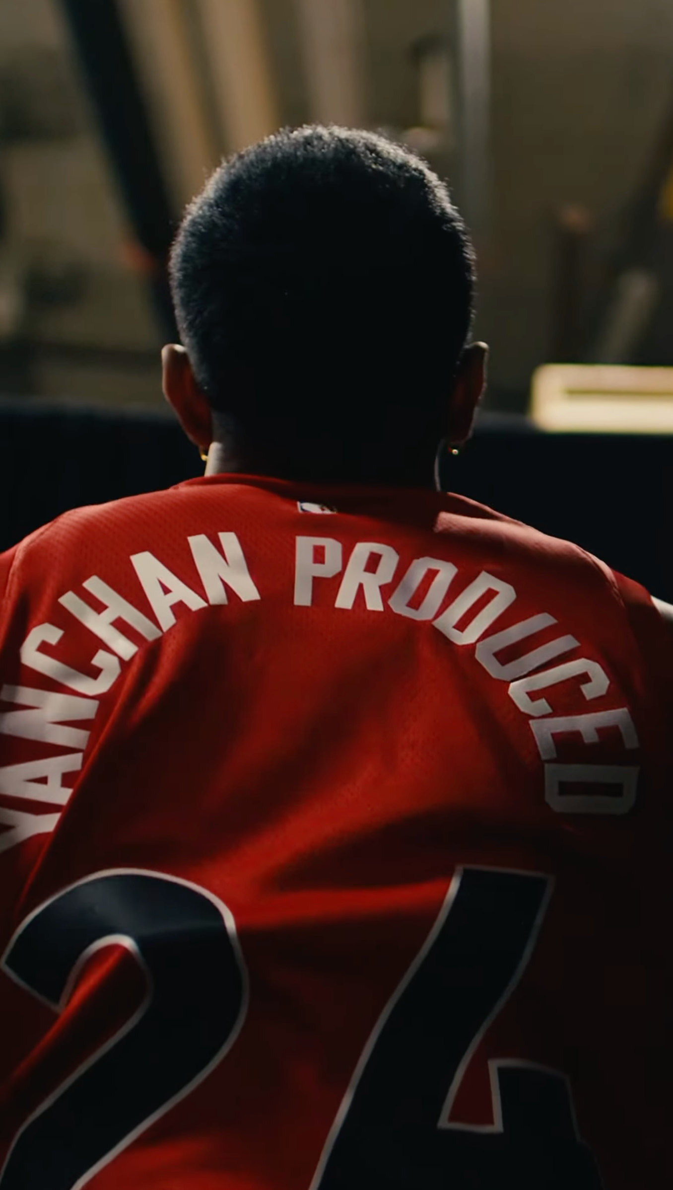Red sports jerseys with white text viewed from behind in dark lighting.