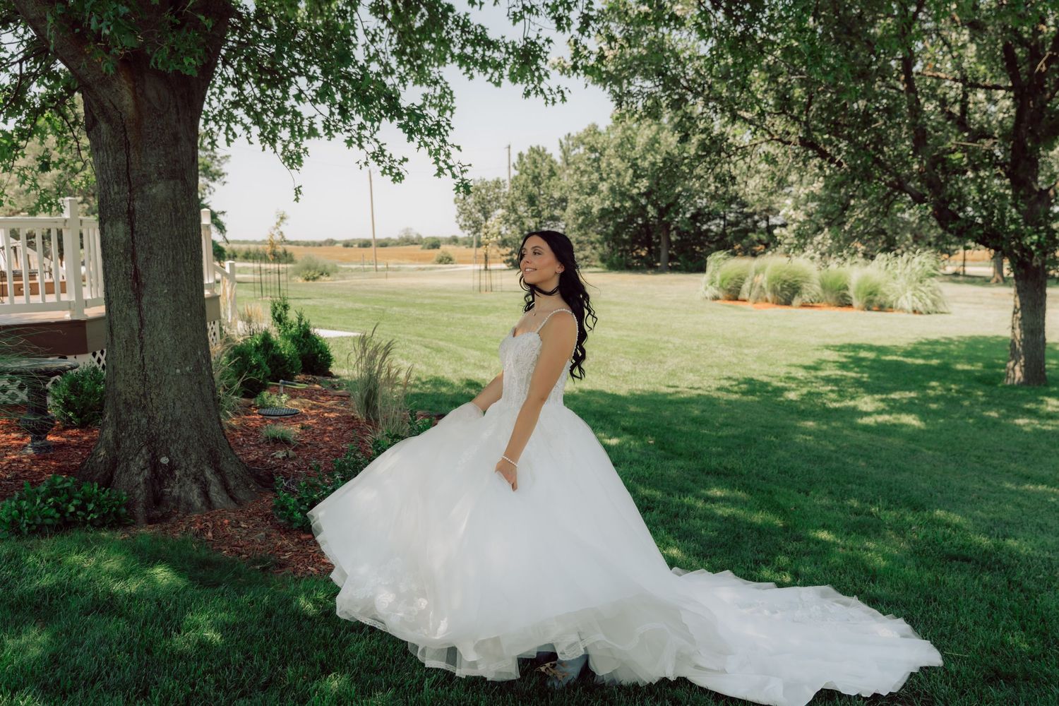 A white wedding dress with a full tulle skirt flows gracefully across a wooden porch.