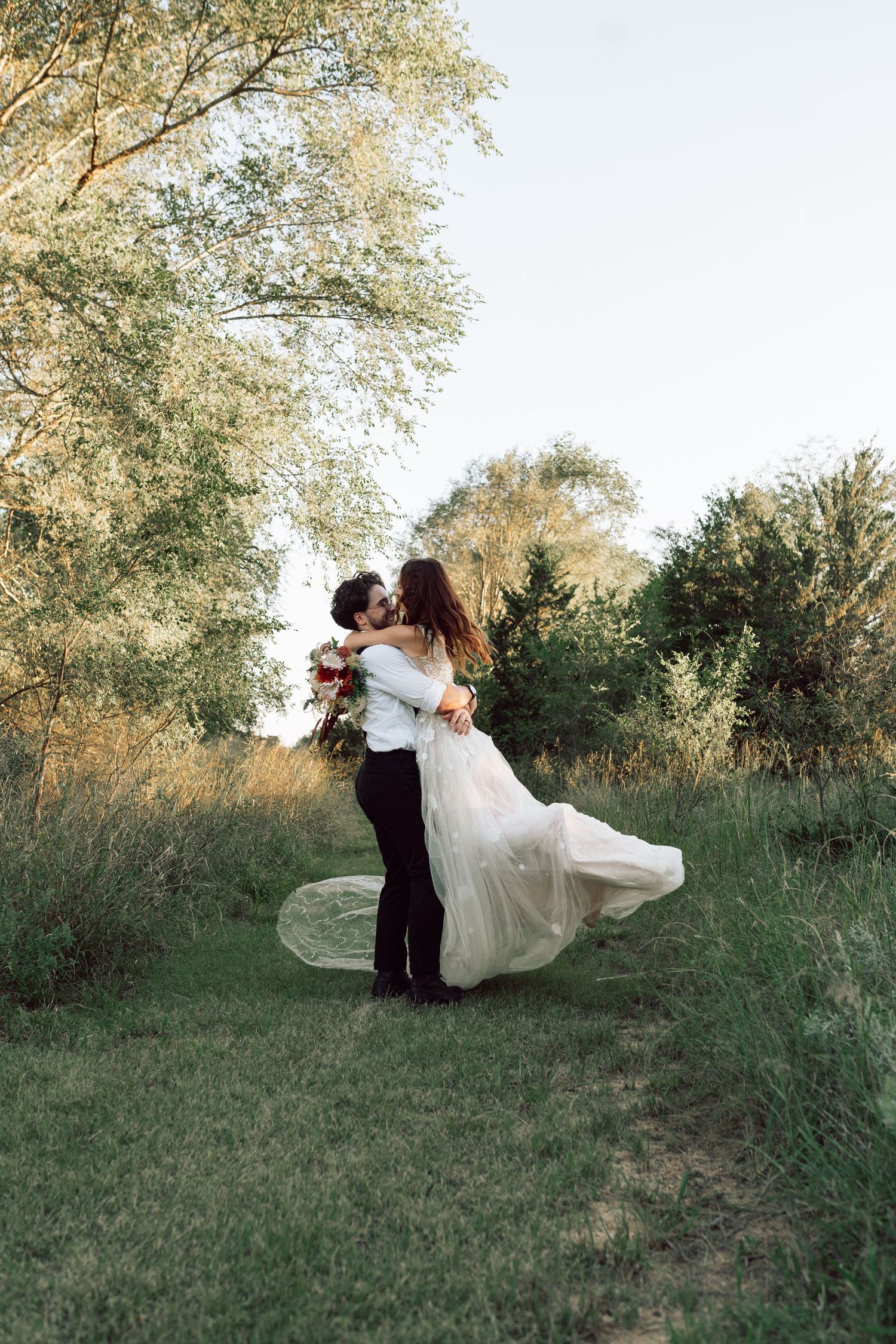 A romantic dance dip pose captured in a sunlit outdoor setting.
