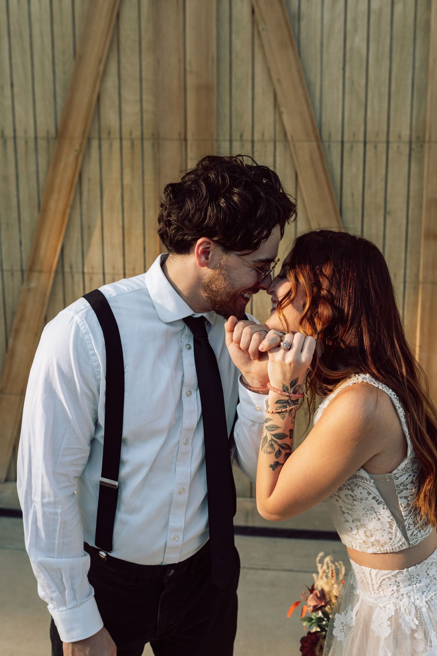 Romantic moment shared between a couple in formal attire by wooden barn doors.