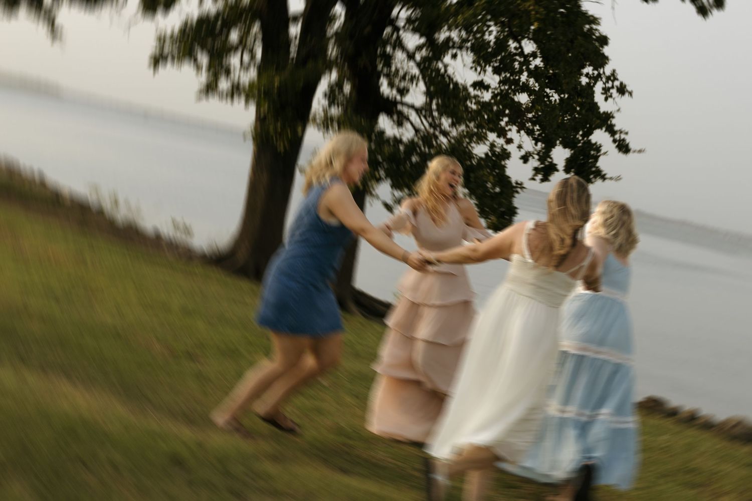 Group in flowy dresses twirl and dance together outdoors.