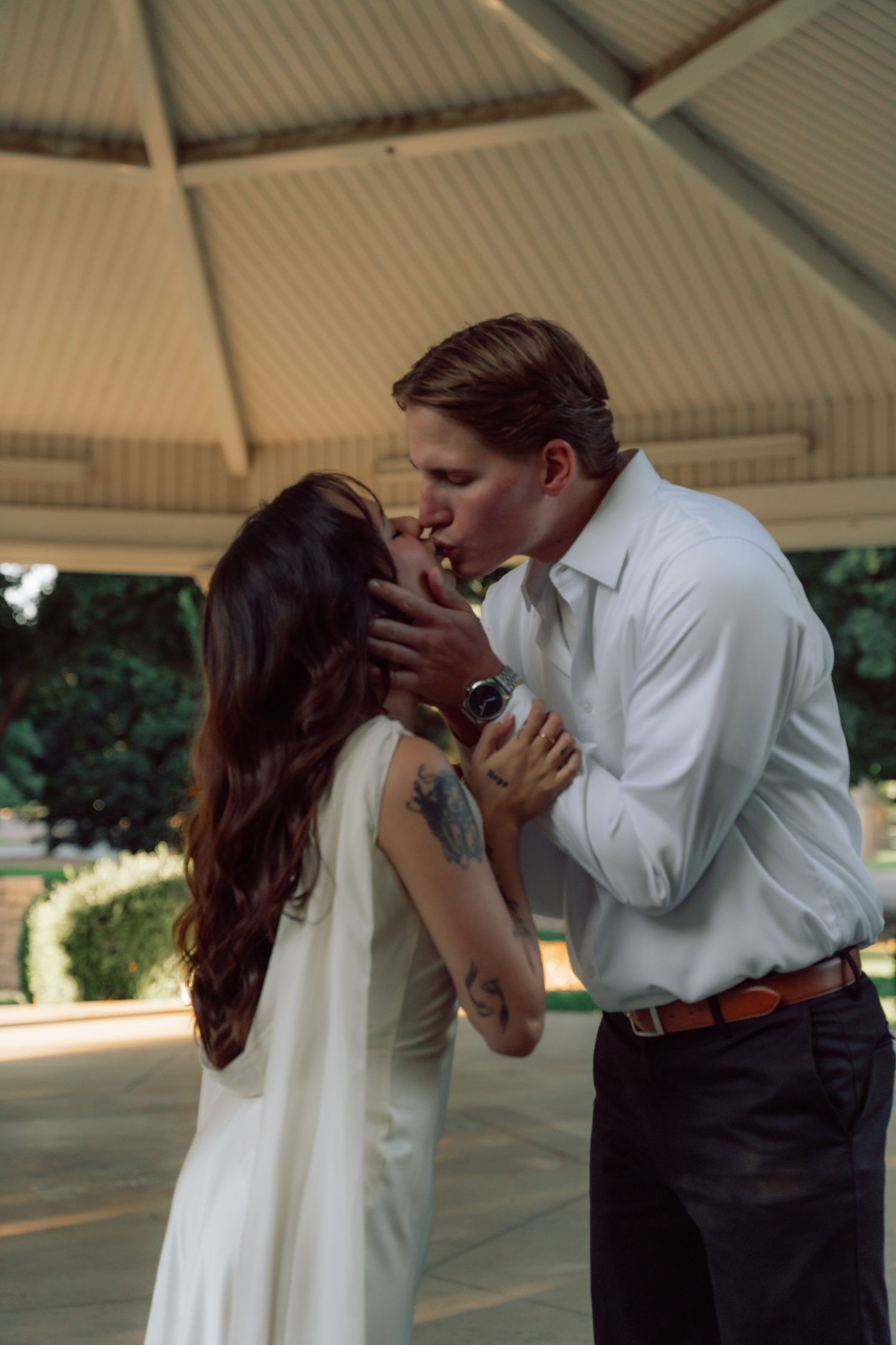 A romantic kiss shared under an ornate gazebo ceiling.